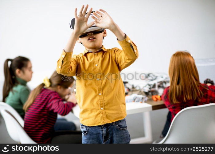 Cute little boy wearing VR virtual reality glasses in a robotics classroom