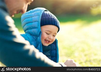 Cute little boy with his father playing outdoors on the fresh green grass field on bright sunny day, happy family with pleasure spending time together, enjoying first spring days. Happy family outdoors