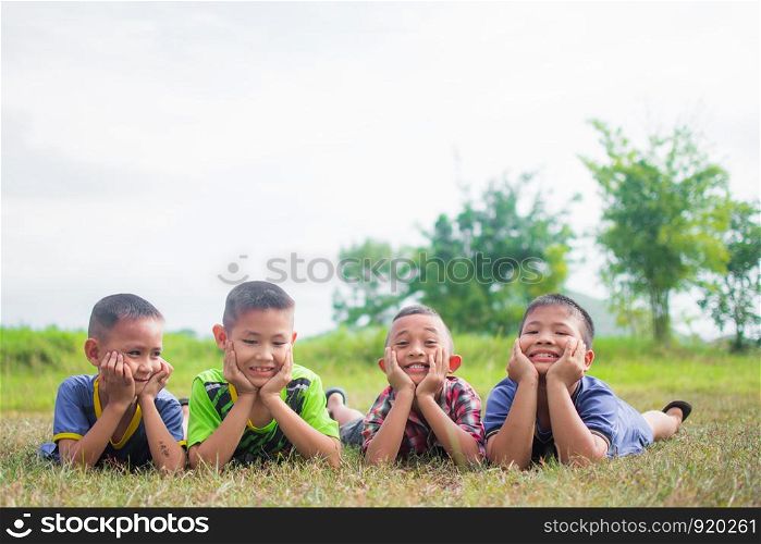 cute little boys lying on grass field and feeling happy, smile and happy together with friends, soft focus.