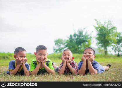 cute little boys lying on grass field and feeling happy, smile and happy together with friends, soft focus.