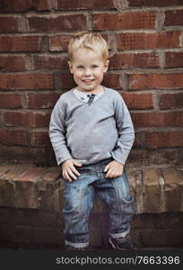 Cute little child posing over old, rusty wall