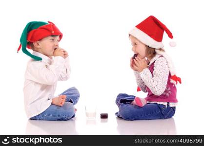 Cute little children with christmas hats eating cookies and laughing