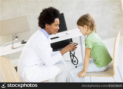 Cute little girl at the pediatrician examination by African american female doctor