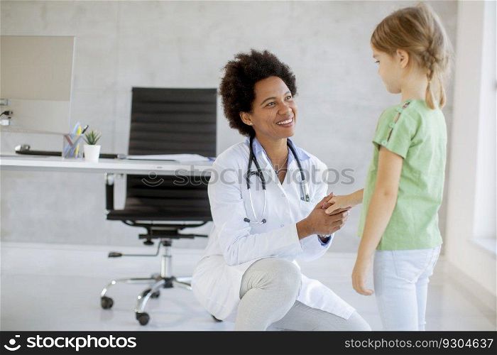 Cute little girl at the pediatrician examination by African american female doctor