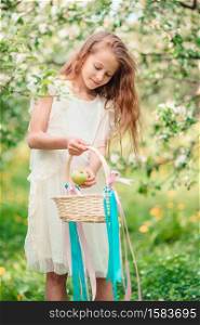 Cute little girl at white dress in blooming apple tree garden. Adorable little girl in blooming apple garden on beautiful spring day