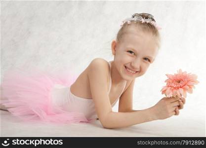 Cute little girl - ballerina lying down the floor with flower in the tutu