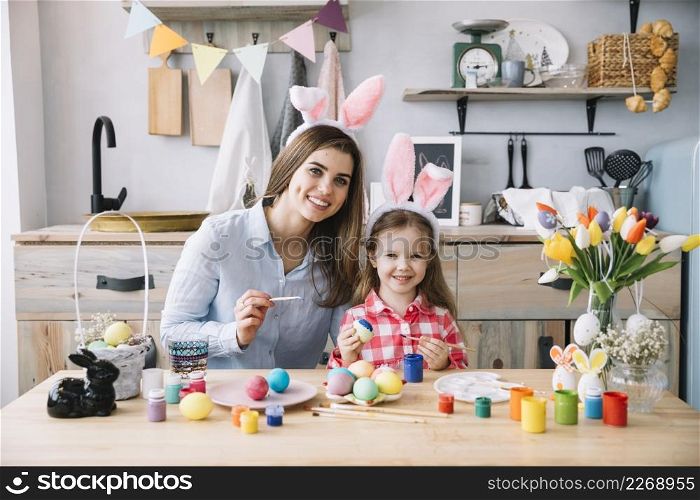 cute little girl bunny ears painting eggs easter with mother
