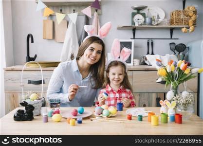 cute little girl bunny ears painting eggs easter with mother