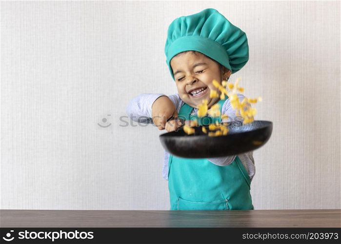 Cute little girl cooking with her frying pan in the kitchen