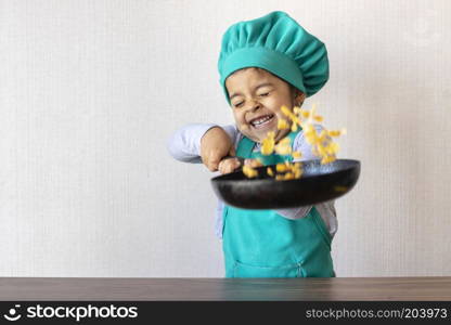 Cute little girl cooking with her frying pan in the kitchen