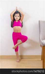 Cute little girl doing yoga at home