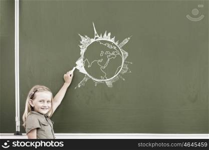 Cute little girl drawing travel concept on blackboard. School girl at blackboard