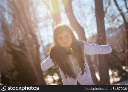Cute little girl having fun outdoors, with pleasure running and jumping in the winter park on sunny day, happy winter holidays. Happy girl outdoors
