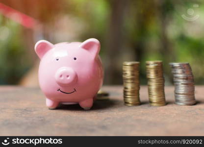 cute little girl holding coin of money and put in pink piggy bank with blur background. subject is blurred.