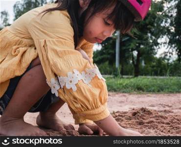 Cute little girl in helmets are playing with sand in park on a sunny summer day, taking a break after cycling practice. develop imagination and exploration.