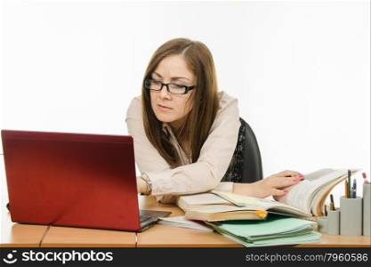 Cute little girl is a teacher sitting at a desk with a laptop, books and notebooks