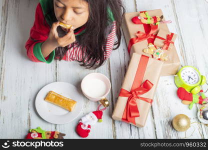 Cute little girl is playing with Santa's cookies and milk at Christmas