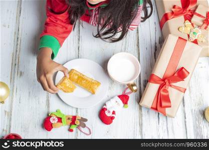Cute little girl is playing with Santa's cookies and milk at Christmas