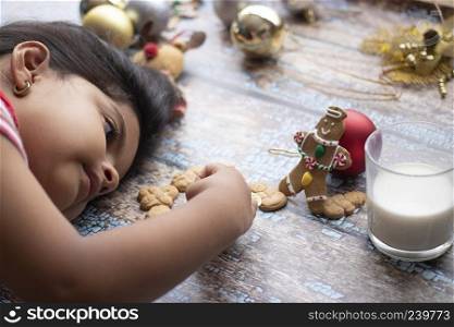 Cute little girl is playing with Santa"s cookies and milk at Christmas