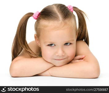 Cute little girl is sitting at the table, isolated over white