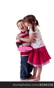 Cute little girl kissing a boy holding a pink heart