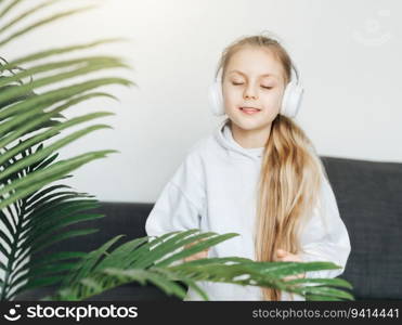 Cute little girl listening to music in headphones  at home.