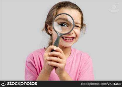 Cute little girl looking through a magnifying glass