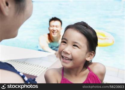 Cute little girl looking up at her mother by the pool