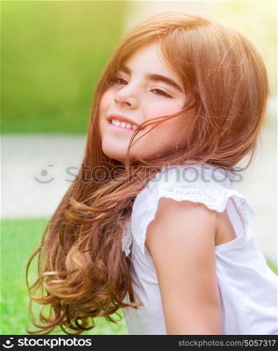 Cute little girl lying down on fresh green grass field; having fun outdoors; relaxing on backyard; happy and carefree childhood