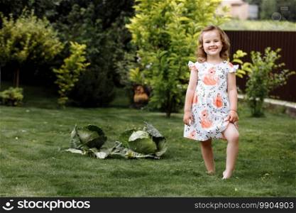 cute little girl on grass with cabbages outdoors at home. cute little girl on grass with cabbages outdoors at home.