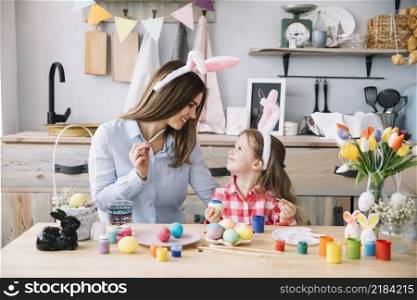 cute little girl painting eggs easter with mother