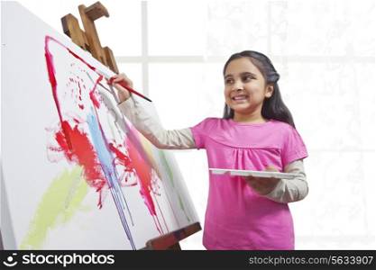 Cute little girl painting on canvas during art class