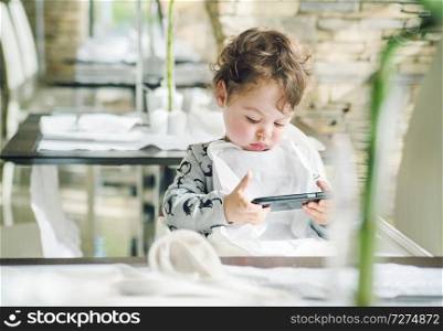 Cute little girl playing games on with a smartphone