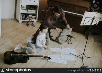 Cute little girl playing guitar with her music teacher in the rustic apartment