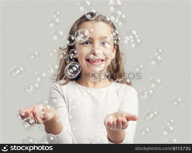 Cute little girl playing with soap bubbles