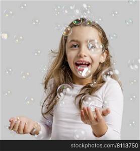 Cute little girl playing with soap bubbles
