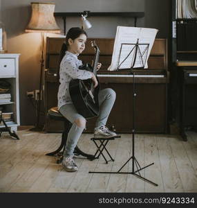 Cute little girl practicing on a acoustic guitar at rustic home