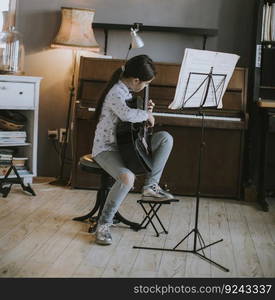 Cute little girl practicing on a acoustic guitar at rustic home