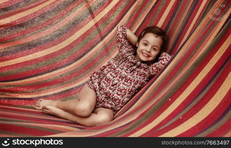 Cute little girl realxing on a colorful hammock