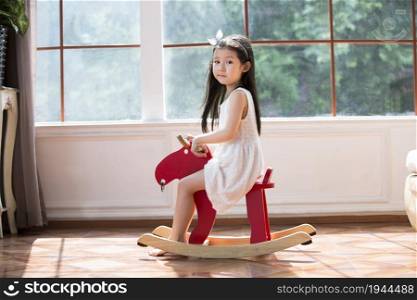 Cute little girl riding a wooden horse