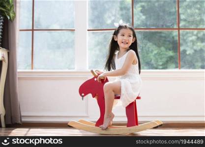 Cute little girl riding a wooden horse