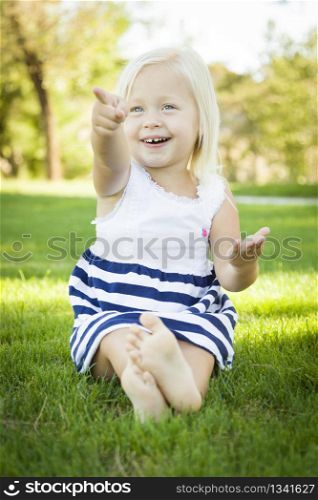Cute Little Girl Sitting and Laughing in the Grass Outside.