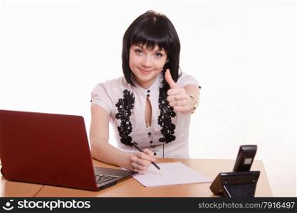 Cute little girl sitting at a table in the call center with laptop in white blouse. Office employee call-Centras smile shows class