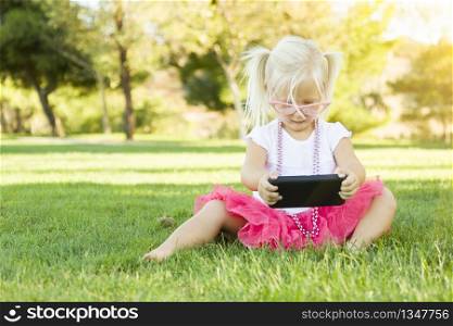 Cute Little Girl Sitting In Grass Playing With Cell Phone.