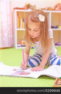 Cute little girl sitting on the floor and drawing picture to the album, having fun at home, happy childhood, having art talent concept