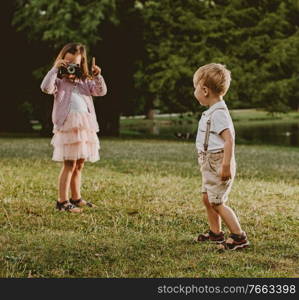 Cute, little girl taking a phto of her younger brother