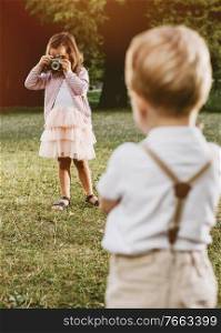 Cute, little girl taking a phto of her younger brother