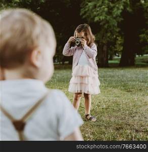 Cute, little girl taking a phto of her younger brother