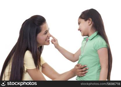 Cute little girl touching mother&rsquo;s nose over white background