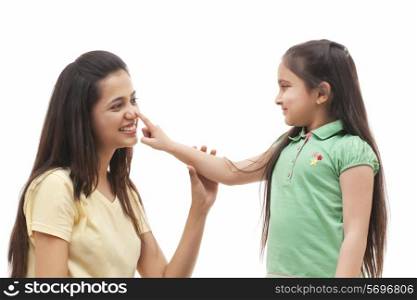 Cute little girl touching mother&rsquo;s nose over white background